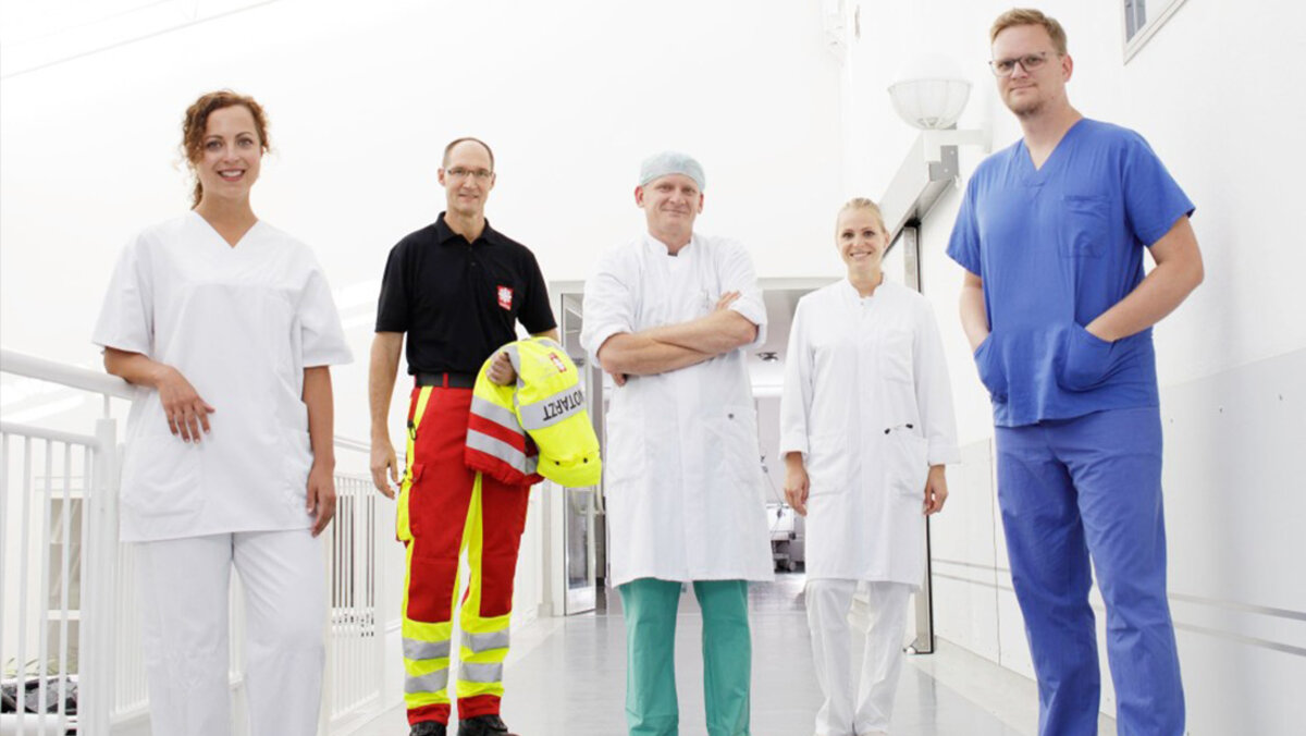 Fünf Mitarbeitende verschiedener Abteilungen des Caritas-Krankenhauses St. Josef auf einem Krankenhausflur