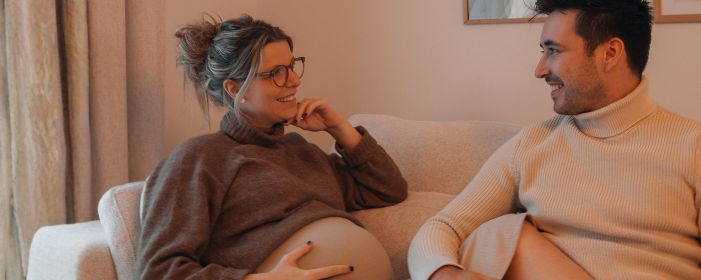 Schwangere Frau und ihr Mann gemeinsam auf dem Sofa