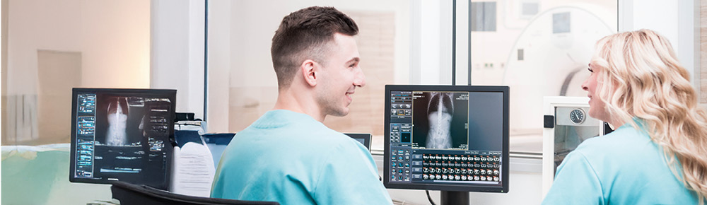 Zwei Fachkräfte die medizinisch-technischen Diensts des Caritas-Krankenhaus St. Josef brachten MRT Aufnahmen und unterhalten sich darüber